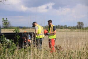 Humane Solutions technicians in the field wearing high-visibility vests, preparing equipment for pest control work.